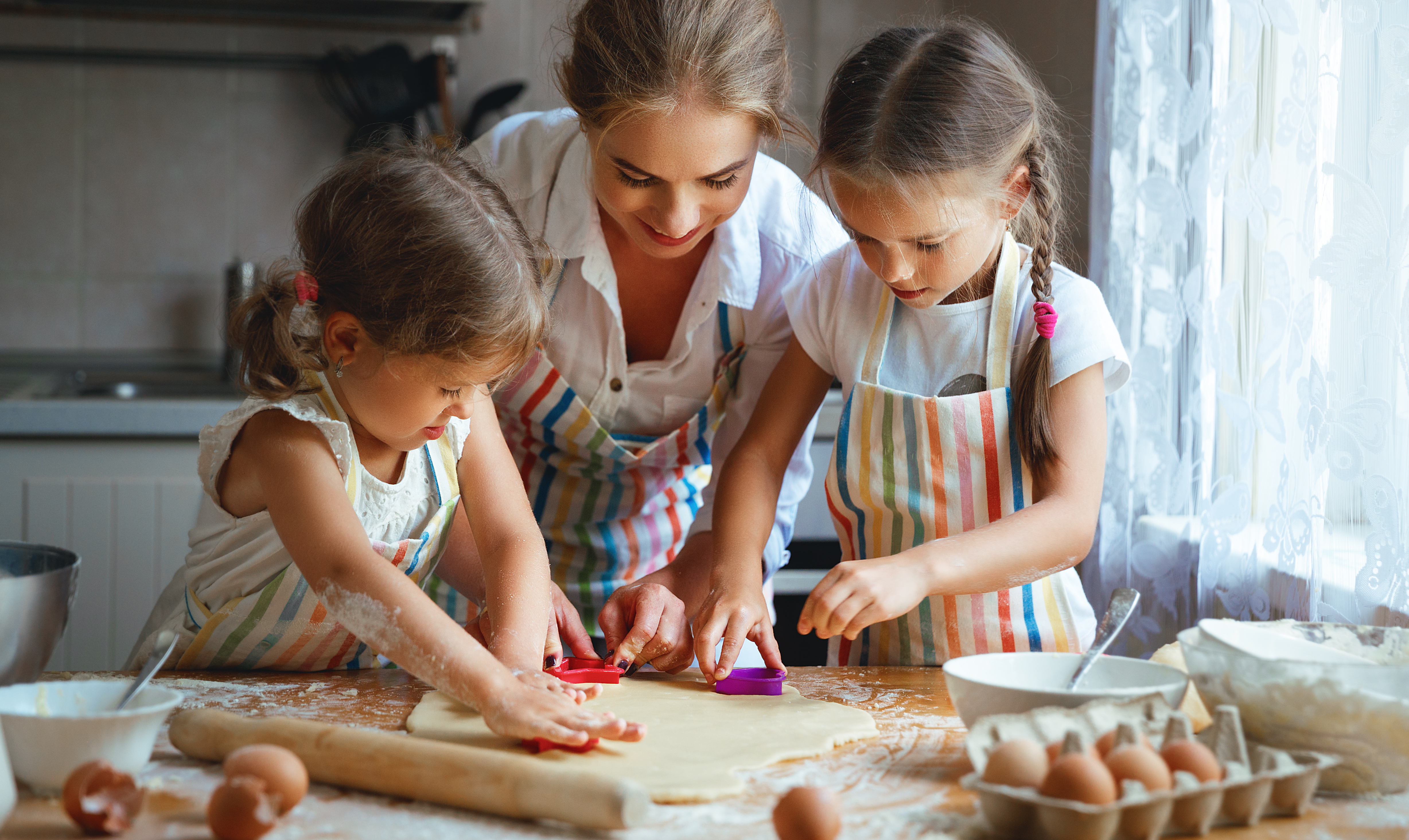Mom and two kids rolling out dough